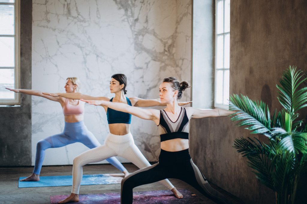 Showing three girls in yoga warrior two pose. This pose is part of the main section for the beginner yoga flow sequence.