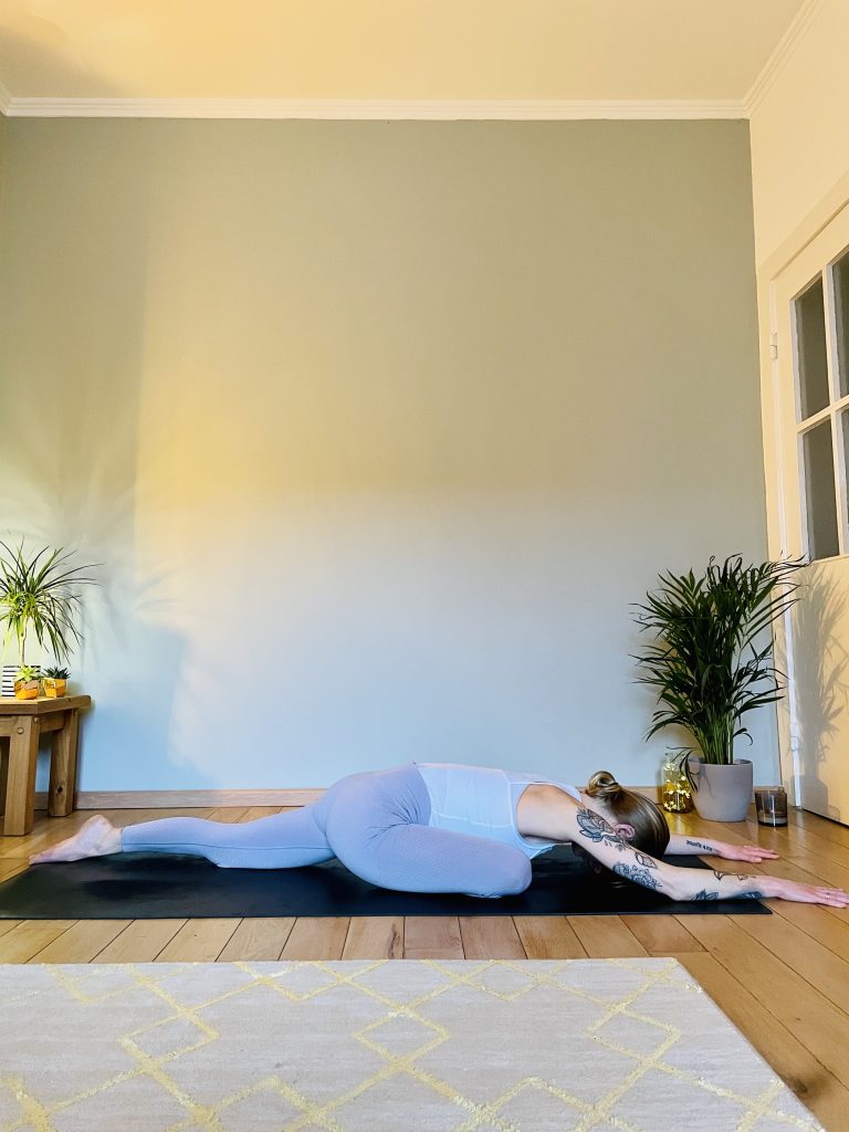 Image depicting a woman practicing the yoga pose "pigeon" viewed from the side in a variation of the pose - a great yoga pose for opening the hips.