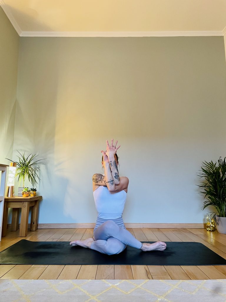 Woman practicing yoga for opening the hips, in this image it is gomukhasana, or cow-face pose. 