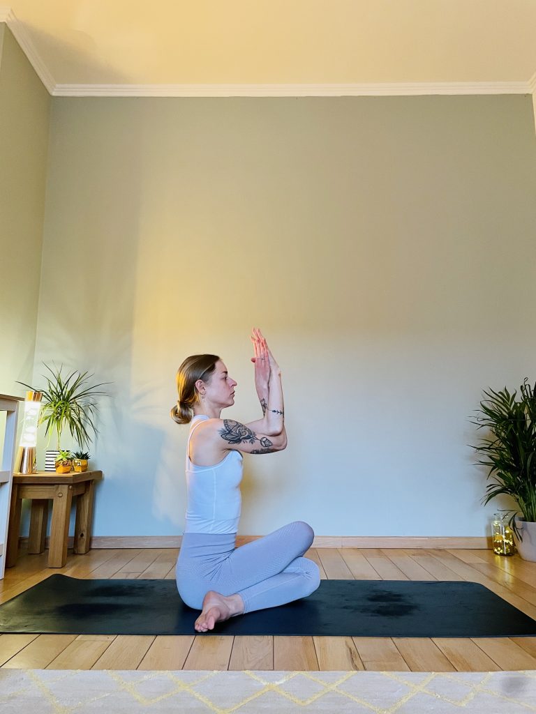 Woman practicing the yoga hip opener Gomukhasana - in this image viewed from the side.