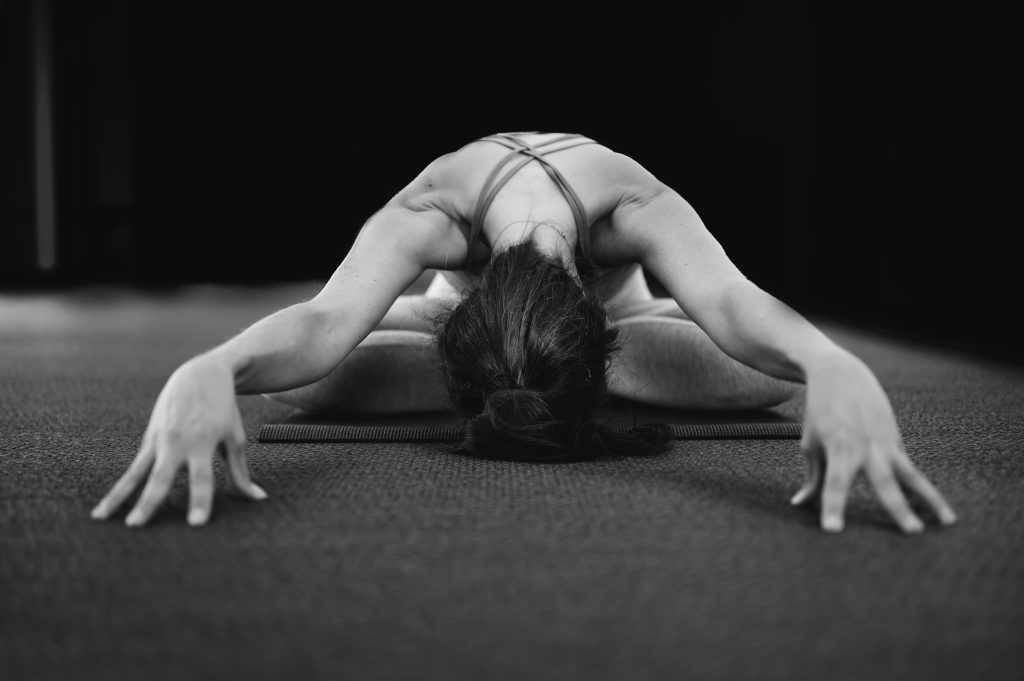 Black and white image showing a girl in a yoga pose, cross-legged seat.