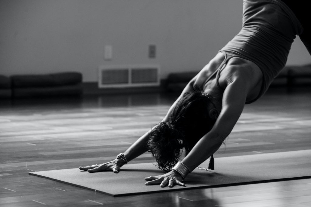 Image in black and white showing a woman in the yoga pose, downward facing dog. Yoga is another great tool for a mindfulness practice, bringing awareness to the body and breath.