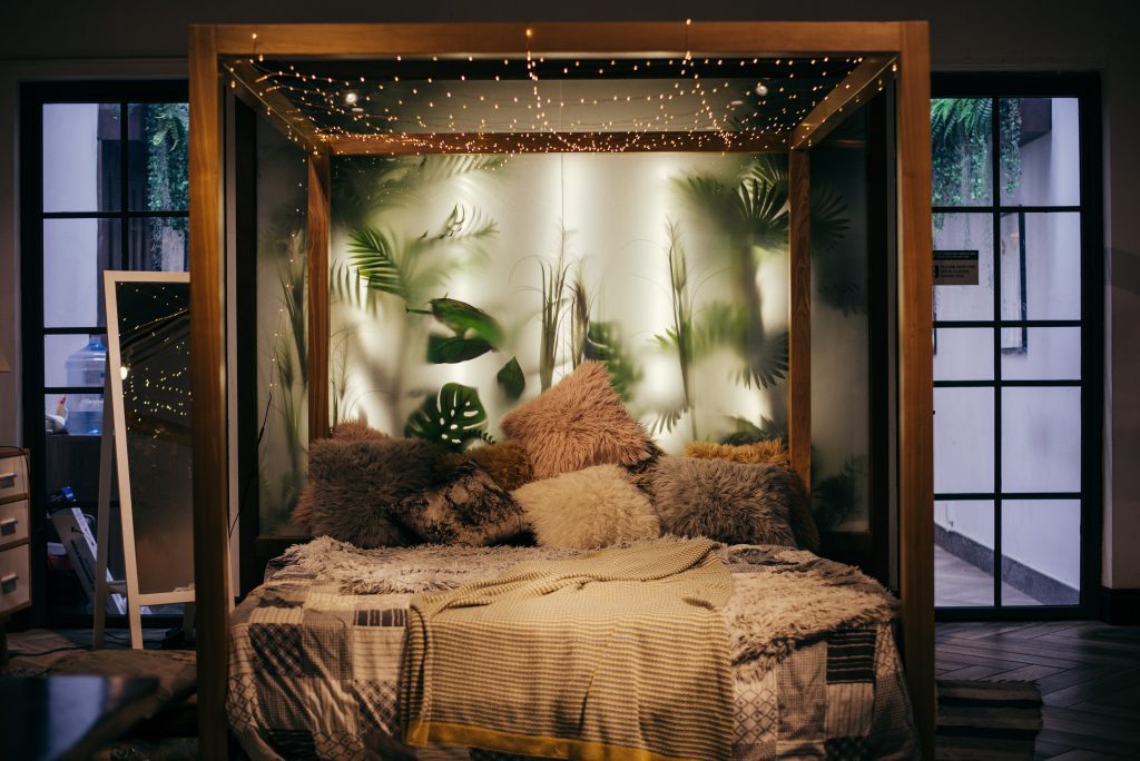 Image showing a cosy bed frame with plants in the background and fairy lights.