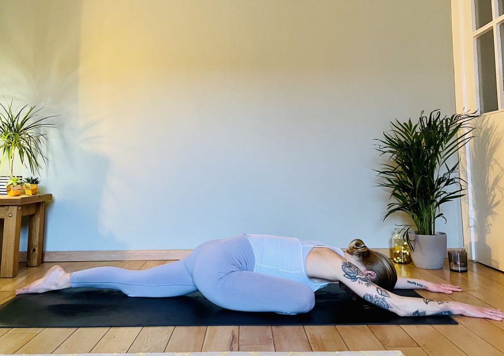 Image showing a girl practicing a variation of the yoga pose pigeon or eka pada raja kapotasana. Pigeon opens the glutes and can greatly help in reducing lower back pain.