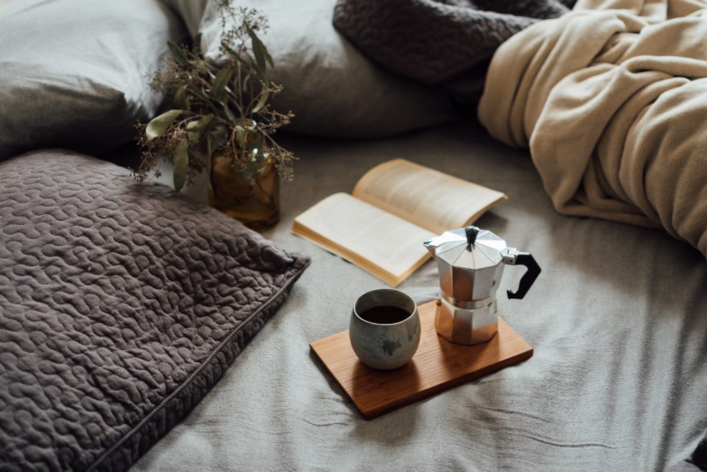 Image showing a book and coffee in the bed. Having an aware and present moment reading a book in bed can be mindfulness. 