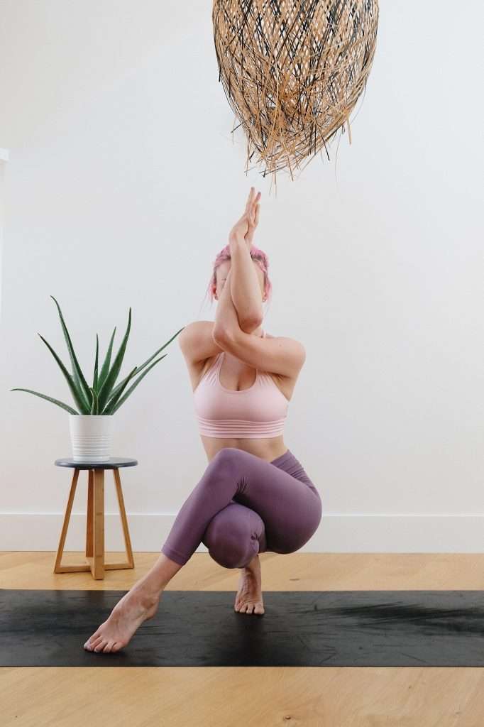 A young woman in an aesthetic balancing yoga pose, which is used to highlight the many benefits of yoga. One of the benefits is improved flexibility and balance.