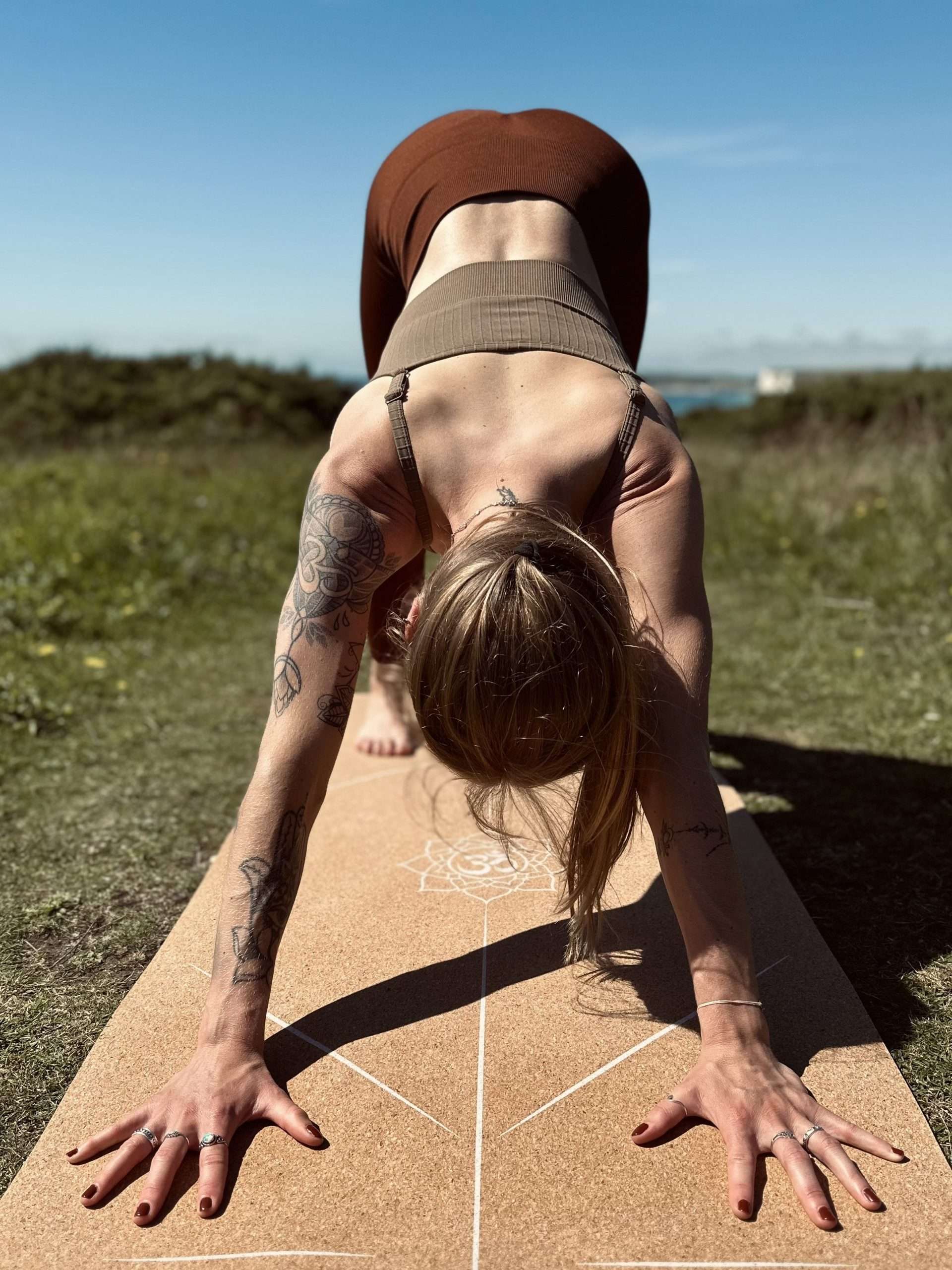 Girl practicing the yoga pose downward dog. Downward Facing Dog can be a good way to practice the foundation for your yoga handstand: hand and finger placement, belly activation, proper breathing.